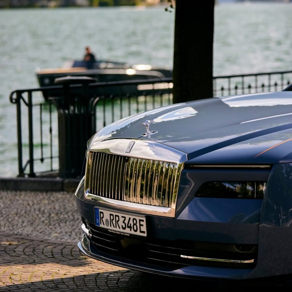 a blue Rolls Royce Spectre park by a lake